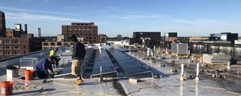 Two men installing solar panels on a rooftop.